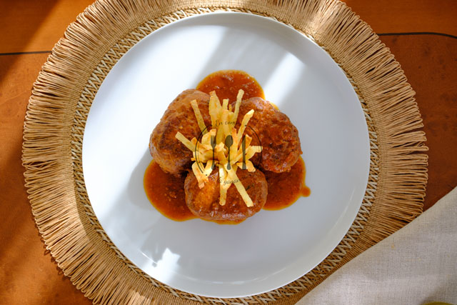 Mini rollos de bonito con patatas paja en plato blanco